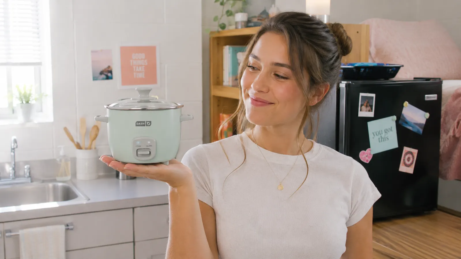 Hand lifting the lid of a Dash Mini Rice Cooker to reveal perfectly cooked rice inside the ceramic pot