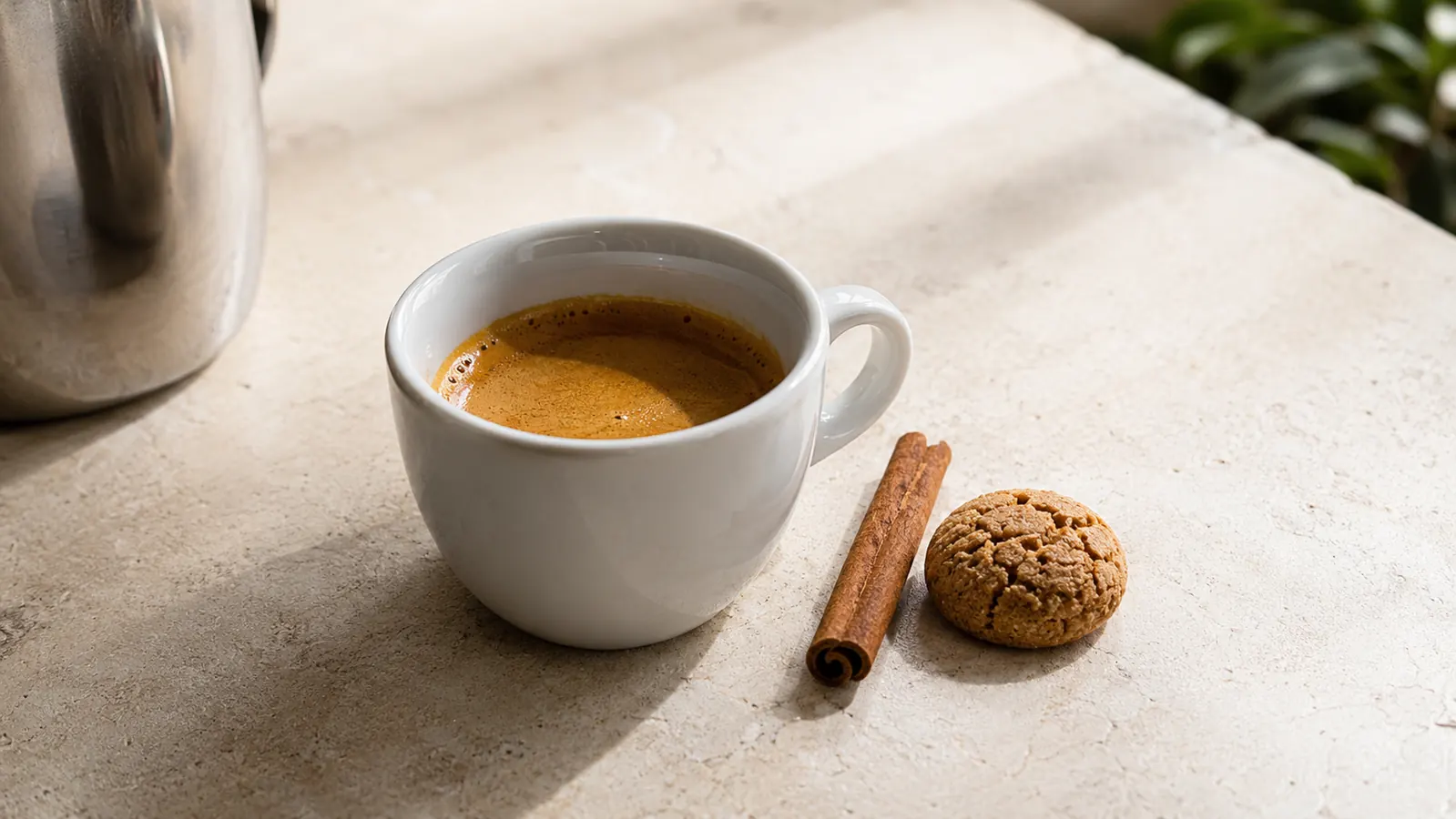 Small espresso cup with crema on top sitting beside the Inissia on a wooden breakfast nook table
